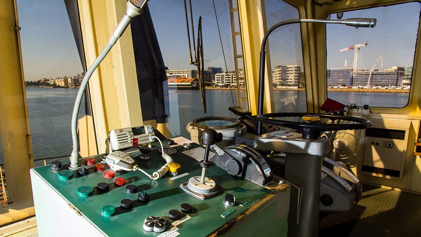 Buttons, joysticks and steering wheel on a tugboat's control panel.
