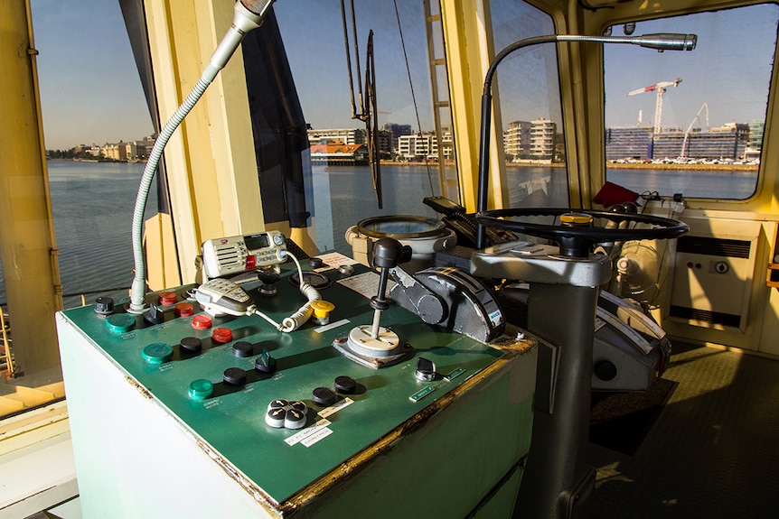 Buttons, joysticks and steering wheel on a tugboat's control panel.