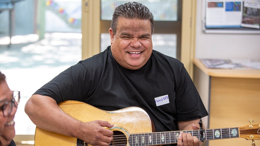 Smiling man is playing an acoustic guitar