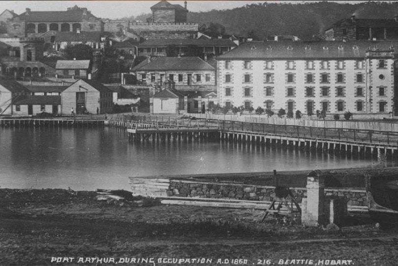 Old photo of buildings on the water, text reads "Port Arthur during occupation AD.1860, 216, Beattie, Hobart"