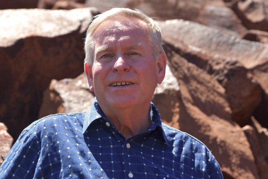 A head and shoulders shot of Colin Barnett standing in front of rocks.