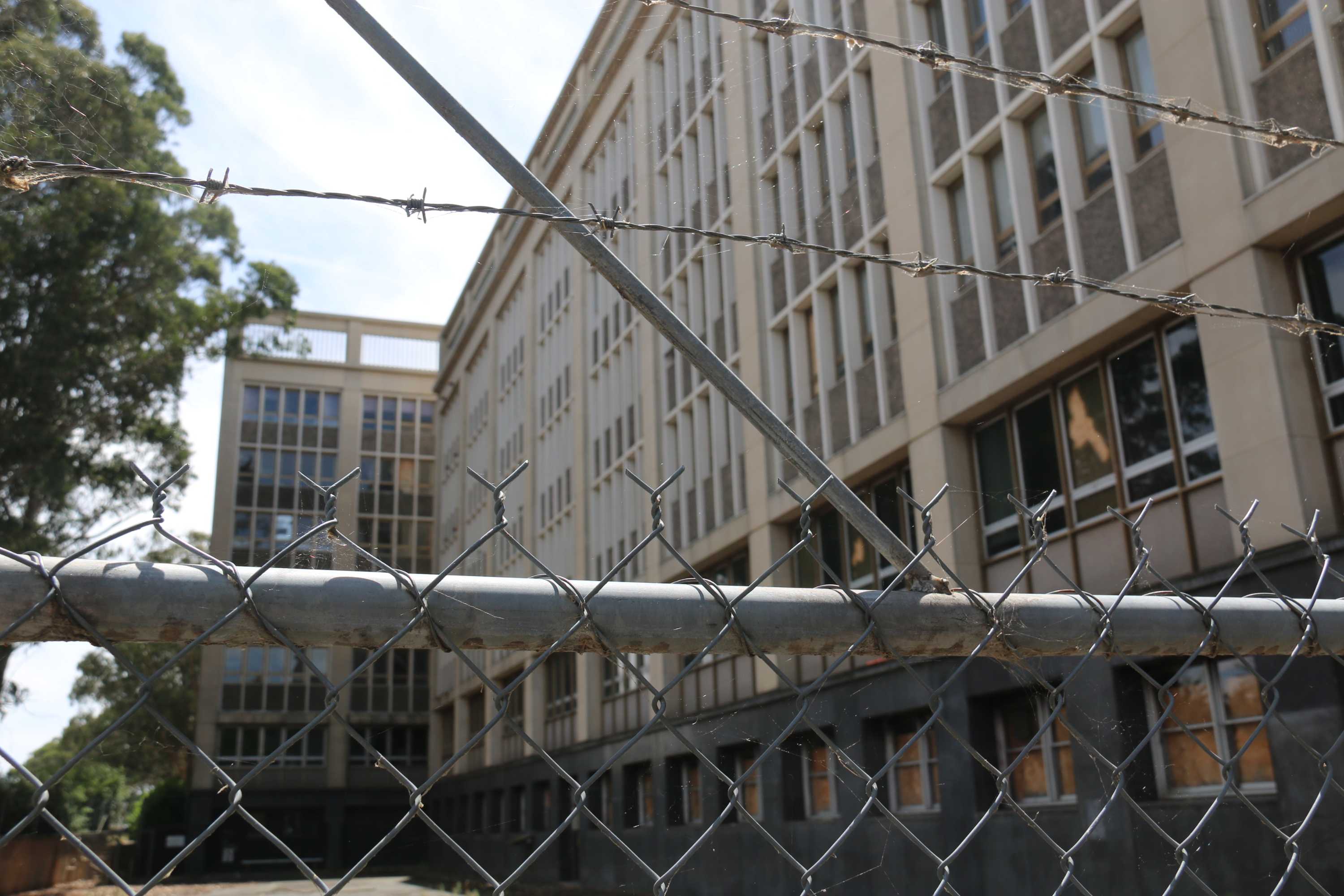 The rear entrance of Anzac Park East behind a study metal fence locked with a chain.