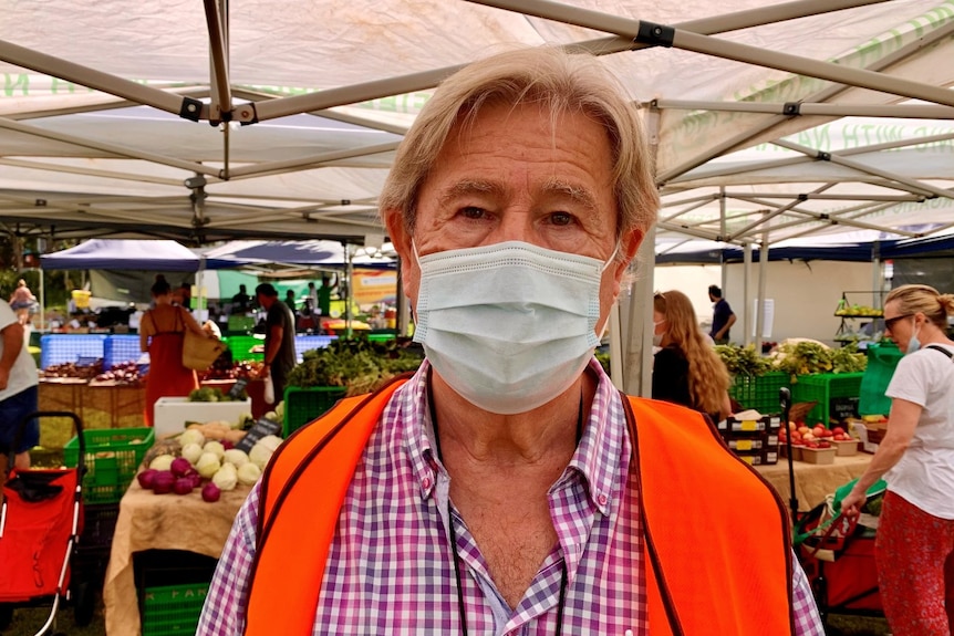 A man wearing a mask at an outdoor market.