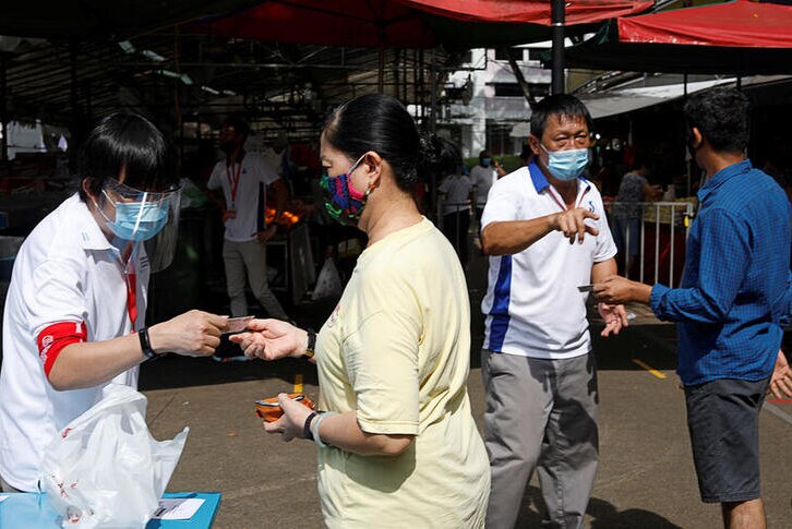 Several people in Singapore are pictured at a market wearing protective masks.