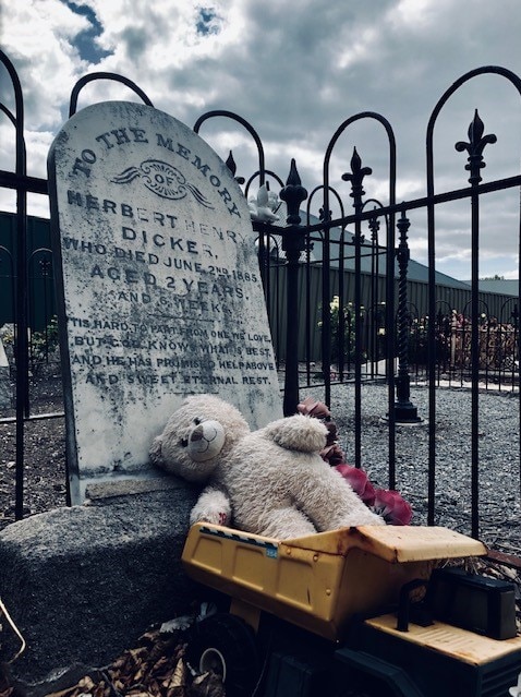 A teddy bear and toy truck on an old grave