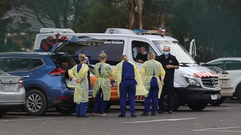 A group of people don personal protective equipment in the carpark outside St Basil's nursing home.