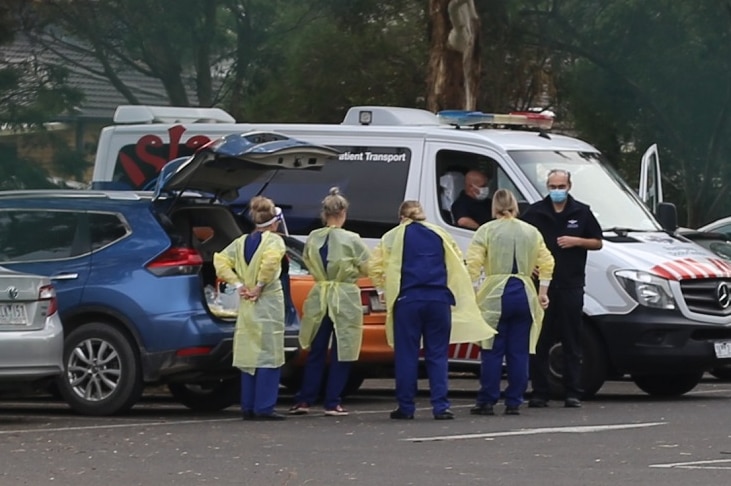A group of people don personal protective equipment in the carpark outside St Basil's nursing home.