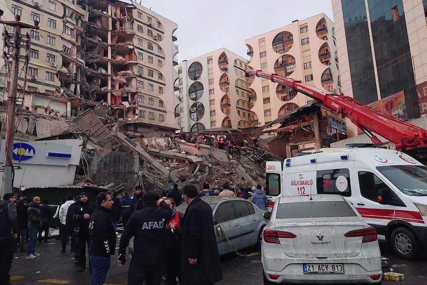 Rescue workers and medical teams try to reach trapped residents in a collapsed building.