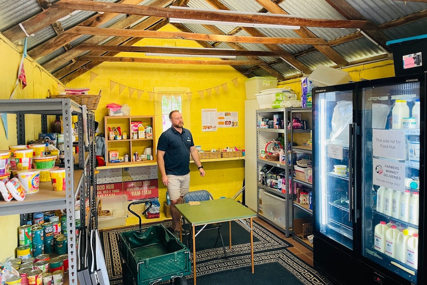 A man in a room full of shelves of food.