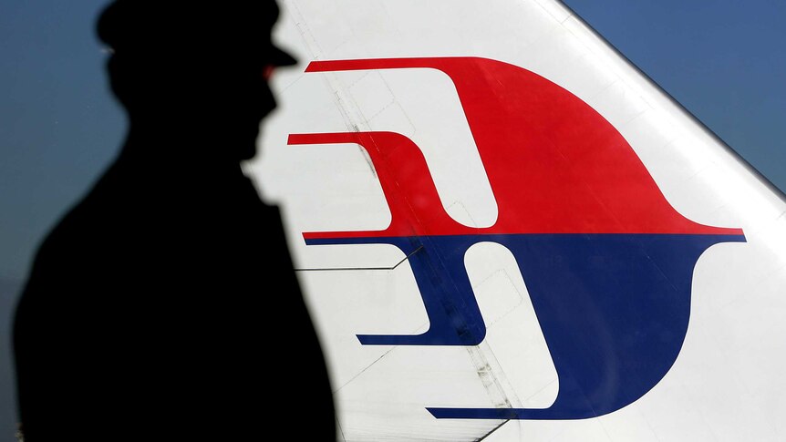 Man silhouetted against a Malaysian Airlines plane tail