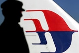 Man silhouetted against a Malaysian Airlines plane tail