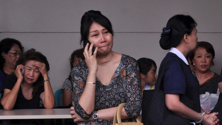 Woman cries on phone while waiting for news from the missing AirAsia flight