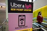 a person stands next to a pink sign providing directions for uber and lyft pickups at an airport in america