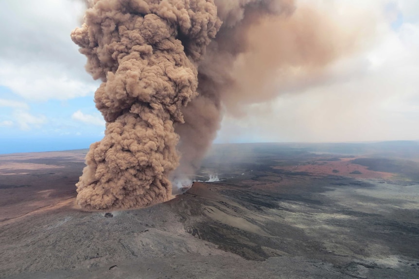 A plume of reddish brown smoke rises from Kilauea volcano.