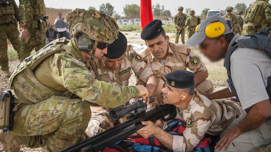 Corporal Stefan Pitruzzello makes a scope adjustment on a rifle while training Iraqi personnel.