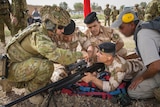 Corporal Stefan Pitruzzello makes a scope adjustment on a rifle while training Iraqi personnel.