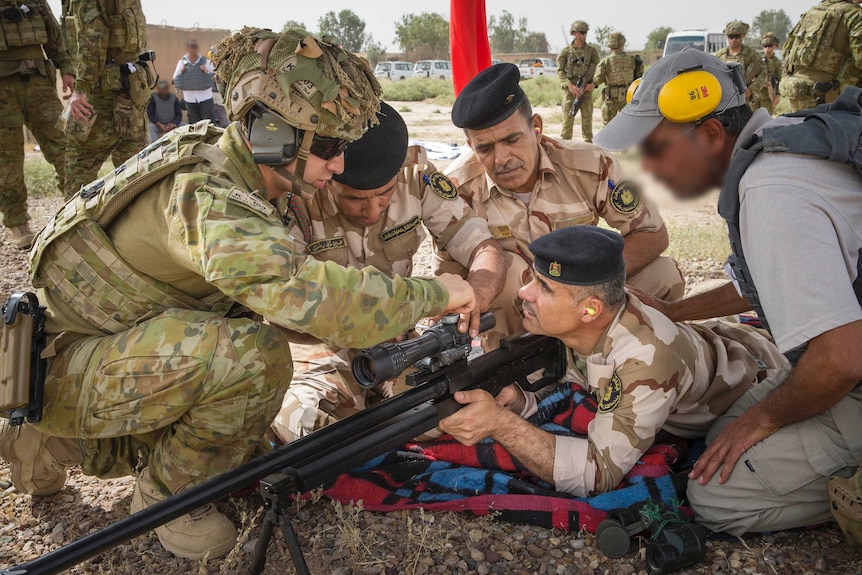 Corporal Stefan Pitruzzello makes a scope adjustment on a rifle while training Iraqi personnel.