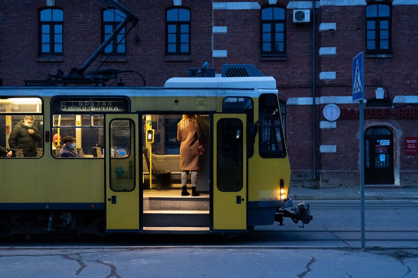 A woman gets on a bus on a street in Lviv.