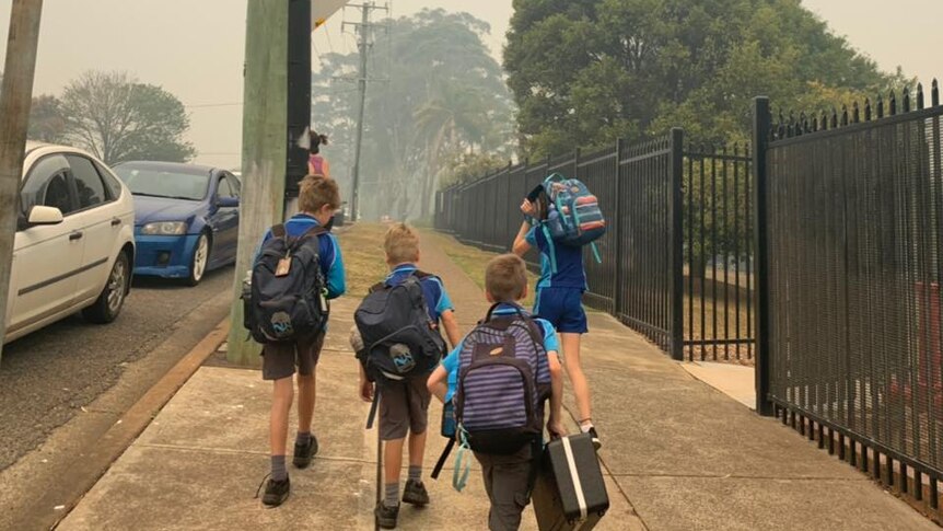 Students leaving school carrying backpacks on a smoky day