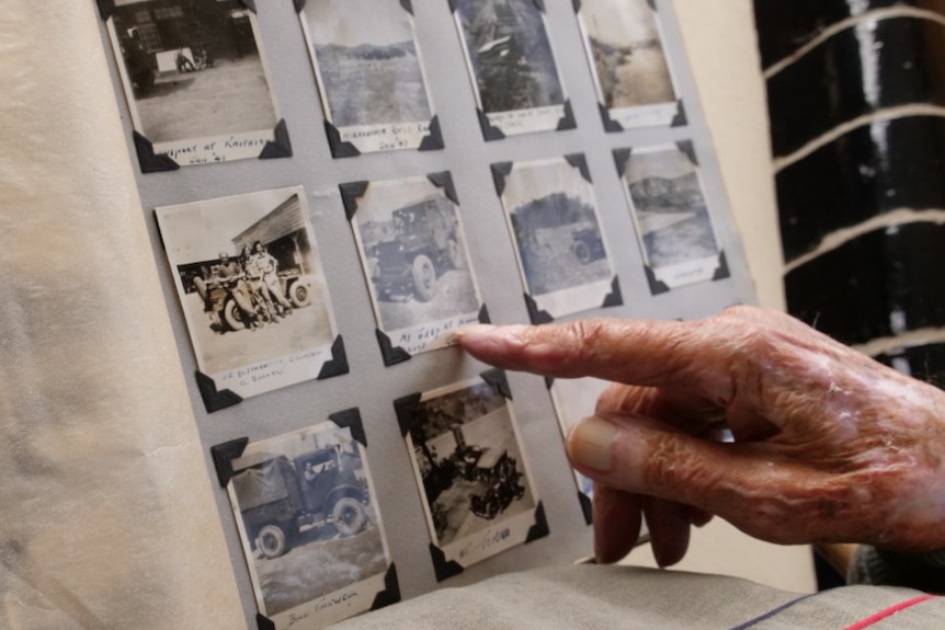 Elderly hand pointing to black and white photographs in an album