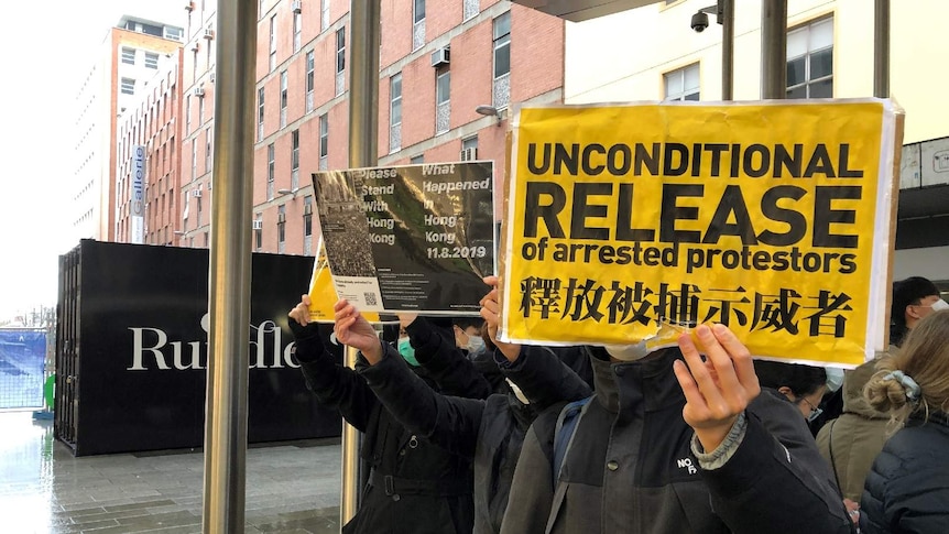 Pro-Hong Kong demonstrators hold up signs at an Adelaide rally.