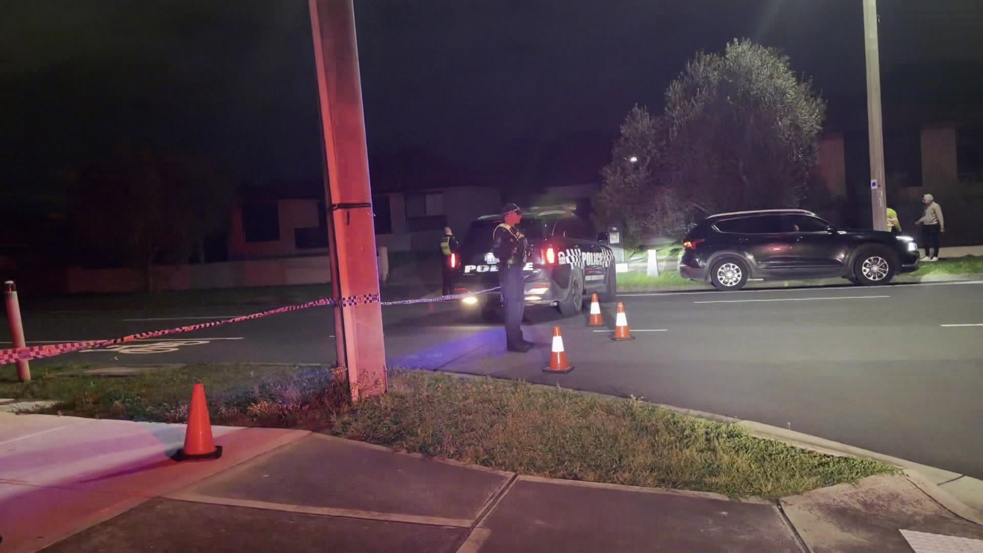 A crime scene at night, with police officers standing beside their vehicles.