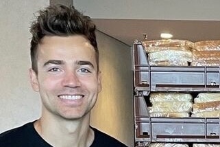 A person standing next to a stack of bread and smiling.