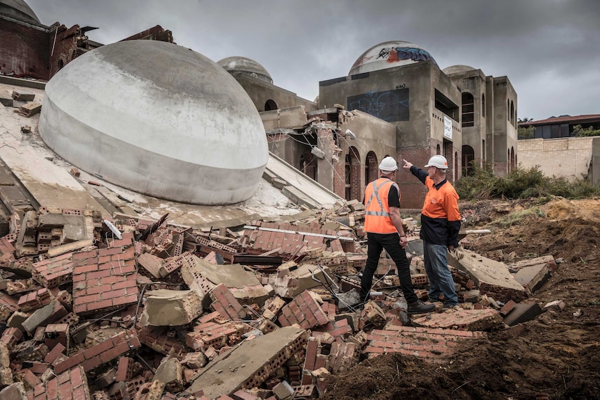 Two workers stand and point at a fallen dome knicked down in the demolition of the Taj on Swan.