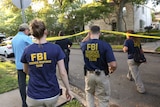 FBI agents walk under police tape.