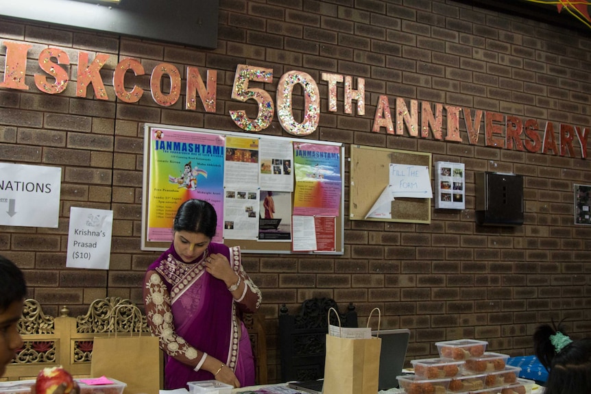 A woman hands out food at the ISKCON 50th anniversary festival.