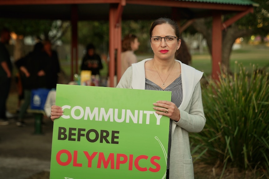 Melissa Occhipinti holds a sign that reads 'community before Olympics'
