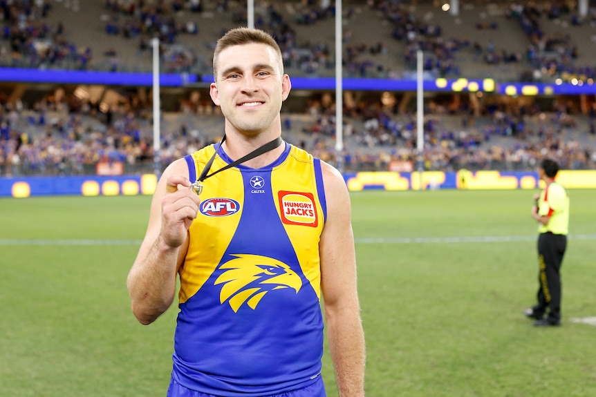 West Coast Eagles player Elliot Yeo smiles while holding a medal. 