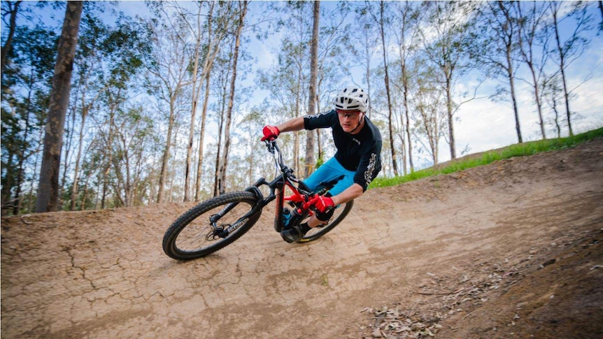 A man on a mountain bike going around a tight corner of a dirt track