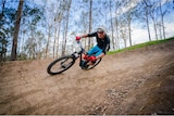 A man on a mountain bike going around a tight corner of a dirt track