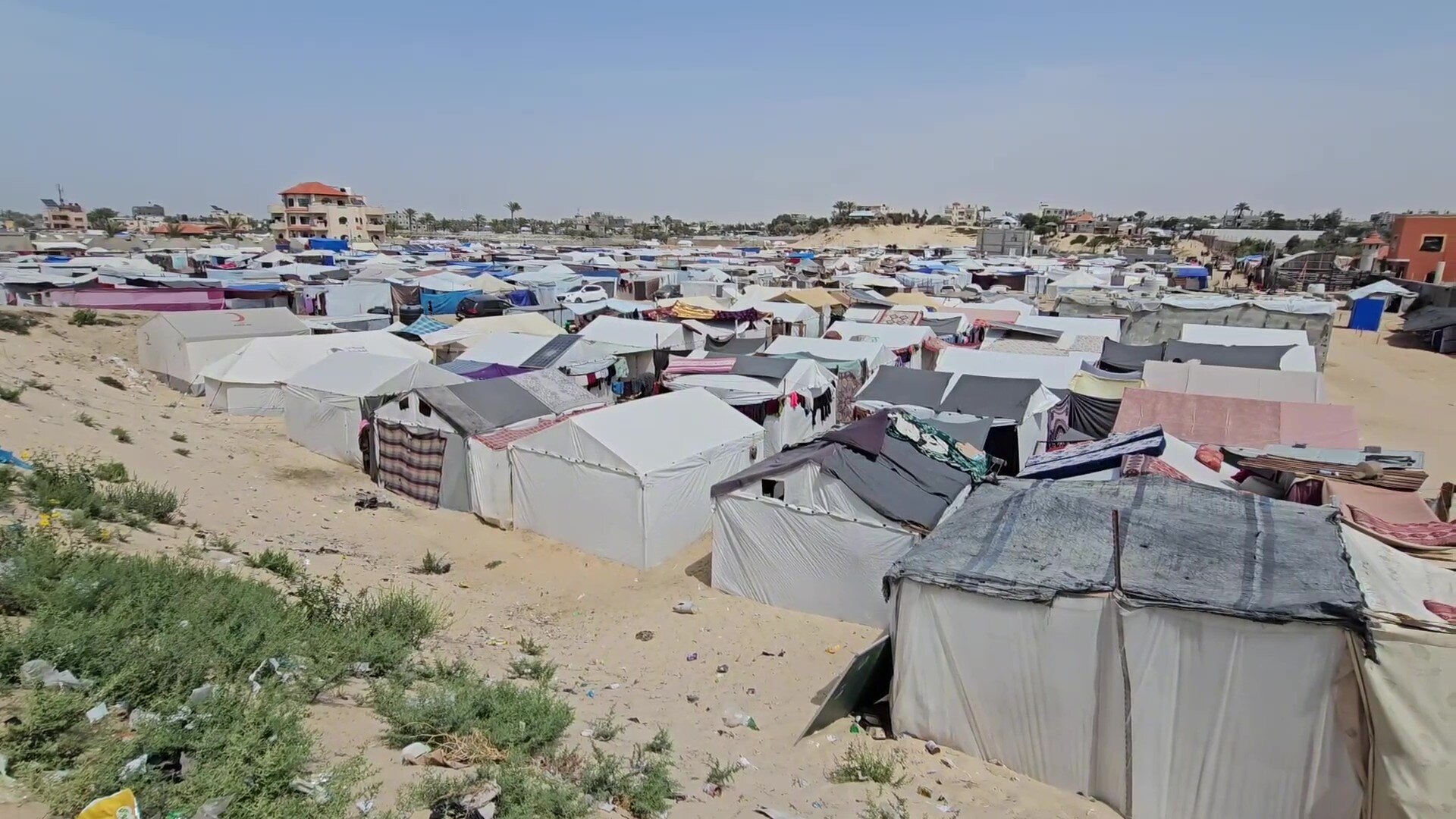 A sandy land area with hundreds of make-shift tents on top