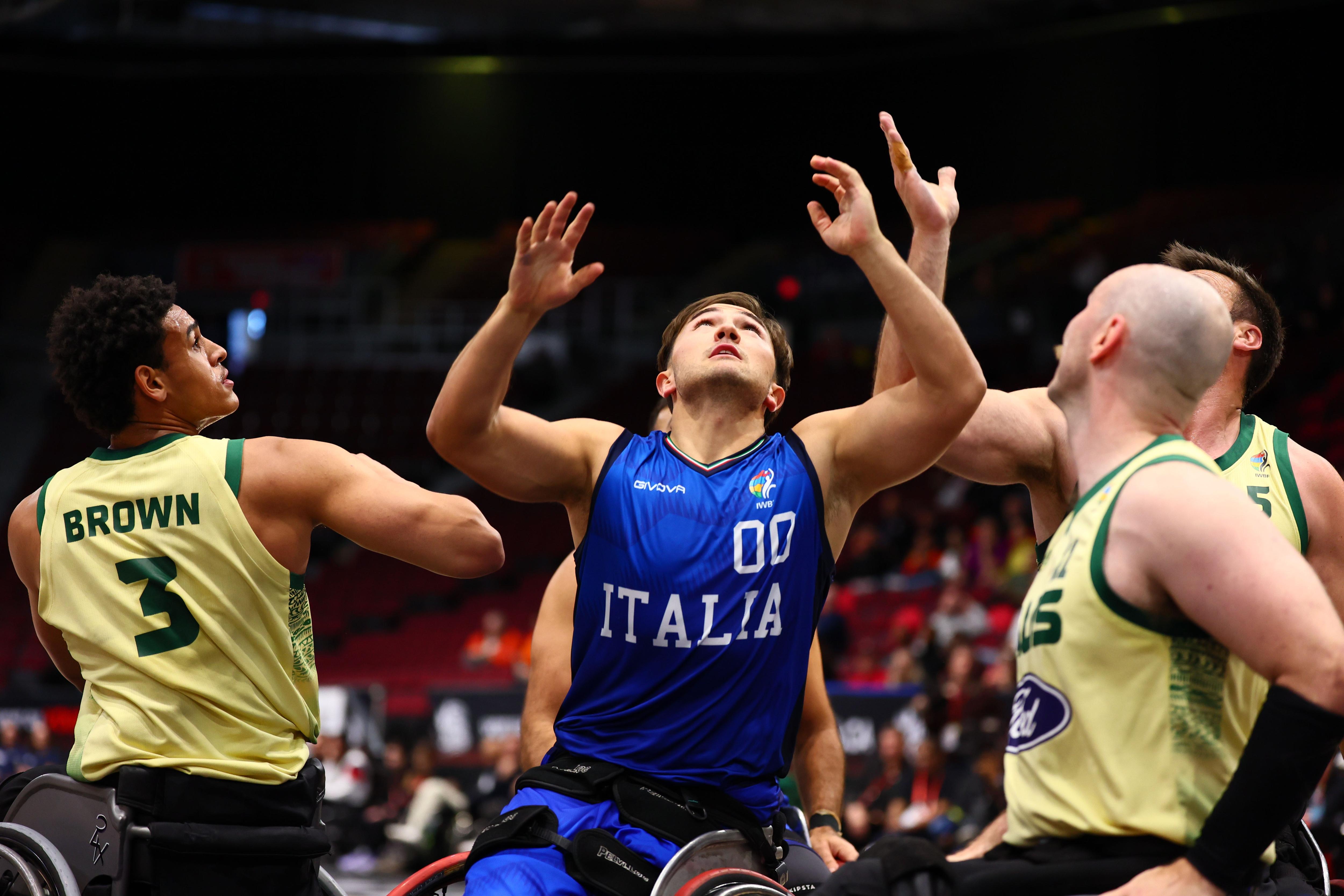 Italian player in blue uniform reaches up with three Australian players around him.