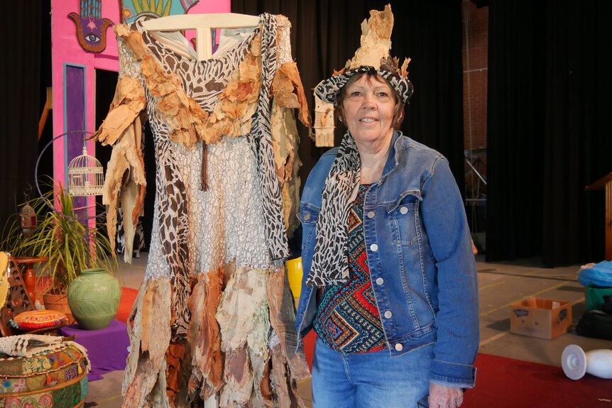 A woman wearing a headdress standing next to a home-made costume. 