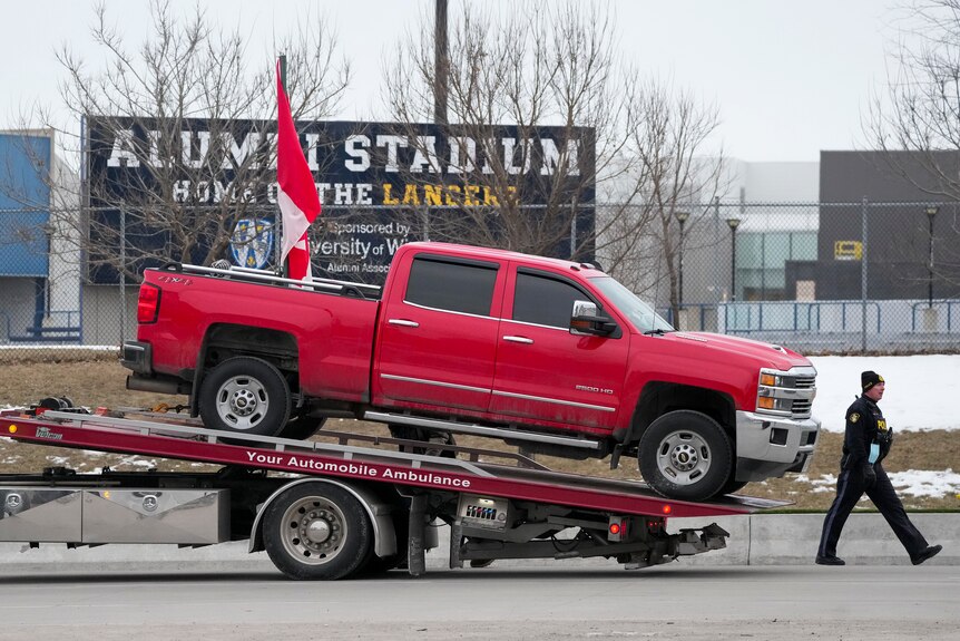 Un camion rosso viene posizionato sul pianale di un carro attrezzi.