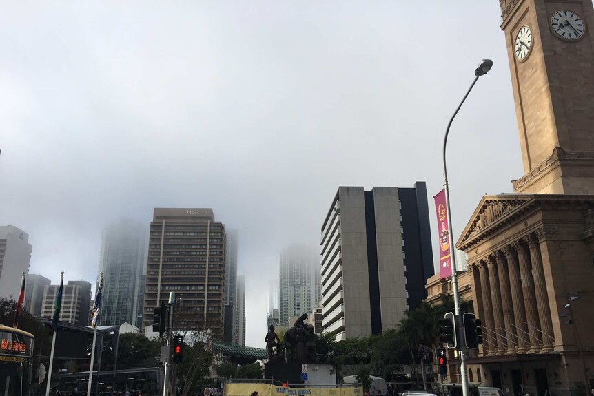 Brisbane residents go about their day as fog begins to lift in the CBD