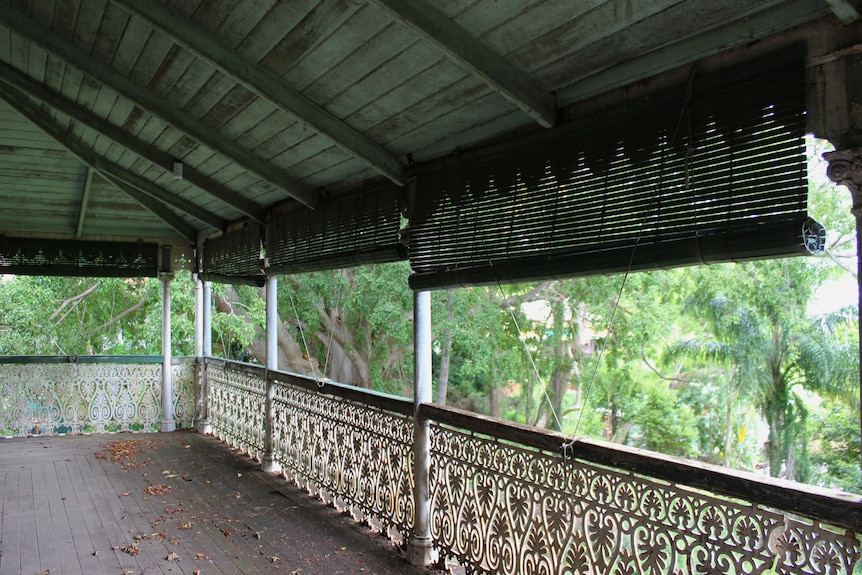 A wide old verandah with ornate wrought-iron railings.