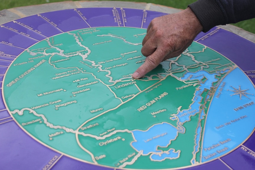 A finger and a hand pointing to an environmental and mining map.