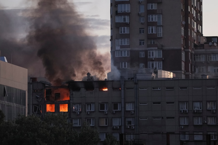 Dark black smoke rises from a flaming building on a cloudy, grey morning in central Kyiv.