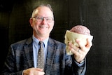 A man holds a model of a brain.
