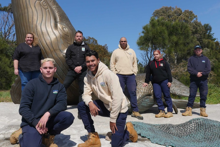 Gamay Rangers stand in front of a whale statue at Kurnell.