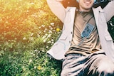 A smiling man wearing headphones plugged into his phone listens to an audiobook.