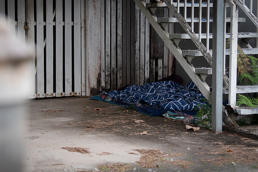 A blanket has been left beneath a wooden staircase of a Queenslander-style building