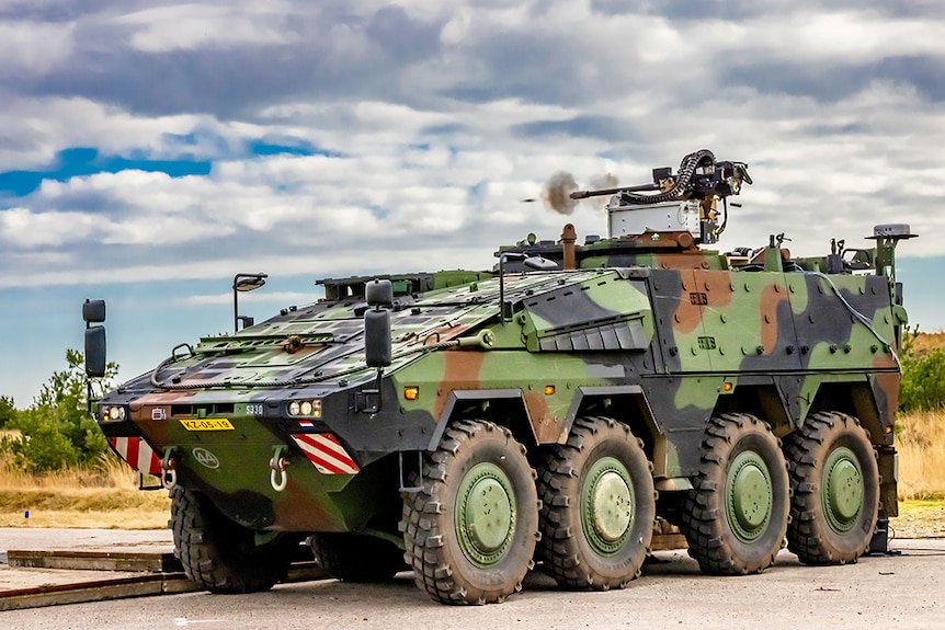 A camouflage pattern army tank with weaponry on the roof