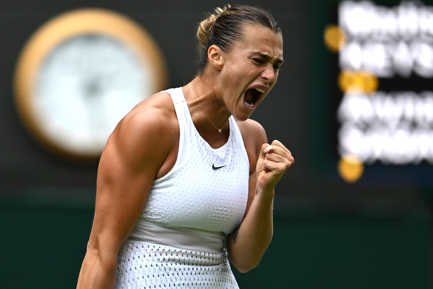 A tennis player clutches her fist and screams.