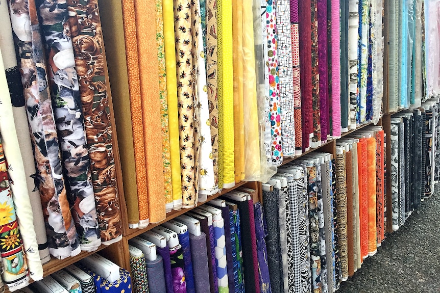 Rows of bright and colourful fabric sit neatly on shelves.
