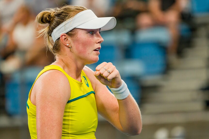 A tennis player pumps her fist in celebration after winning a point.